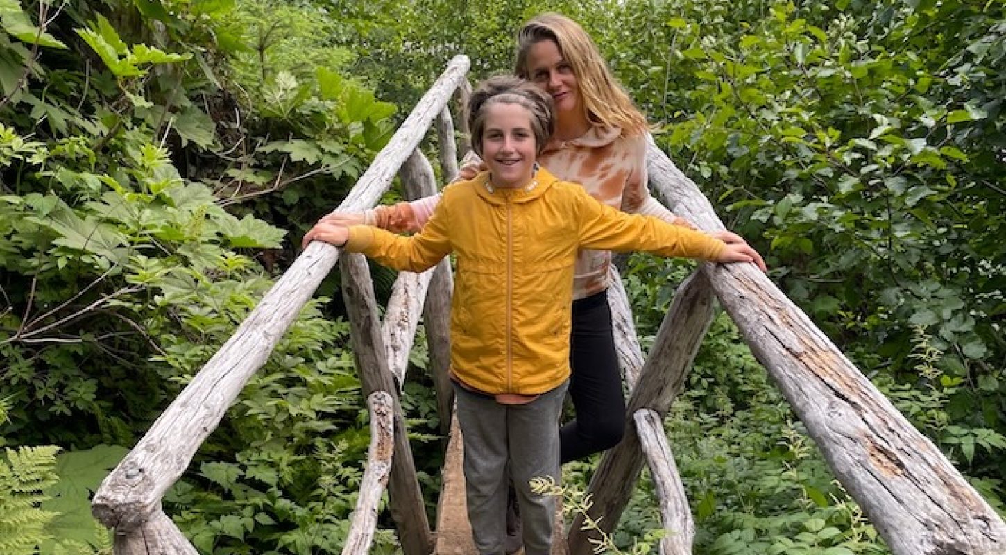 Alicia and Bear on a bridge in forest.