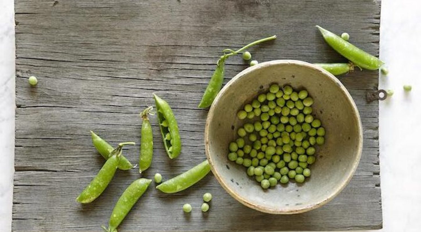 Snap peas on a board and in a bowl.